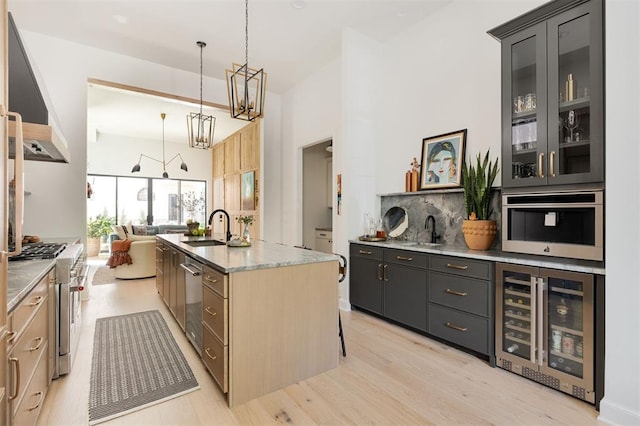 kitchen featuring a center island with sink, sink, wine cooler, light hardwood / wood-style flooring, and decorative light fixtures