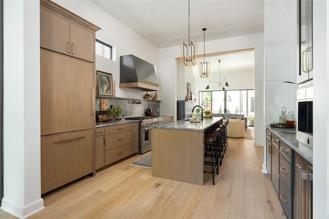 kitchen featuring high end appliances, plenty of natural light, an island with sink, and custom exhaust hood