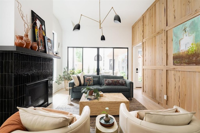 living room featuring a fireplace, light hardwood / wood-style flooring, and wood walls