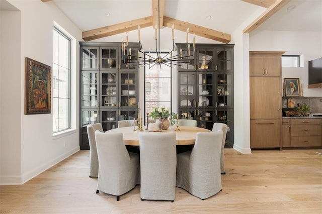 dining space featuring vaulted ceiling with beams, a notable chandelier, a healthy amount of sunlight, and light hardwood / wood-style flooring