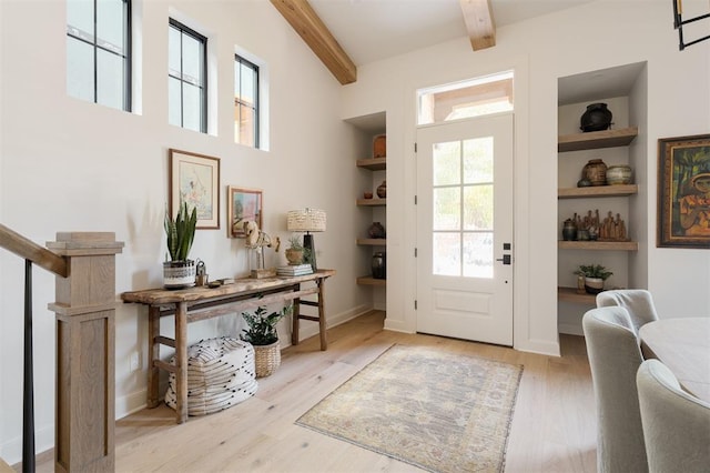 entryway with beam ceiling, light hardwood / wood-style floors, and built in shelves