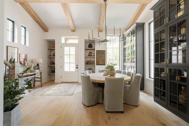 dining space featuring beamed ceiling, light hardwood / wood-style floors, and an inviting chandelier