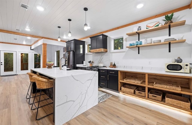 kitchen featuring pendant lighting, light stone countertops, light hardwood / wood-style floors, and a kitchen bar