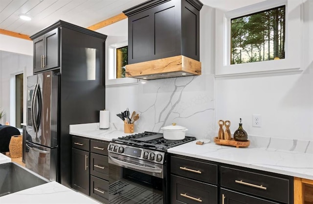 kitchen featuring light stone counters, decorative backsplash, premium range hood, and appliances with stainless steel finishes