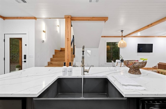 kitchen featuring light stone counters, hanging light fixtures, and sink