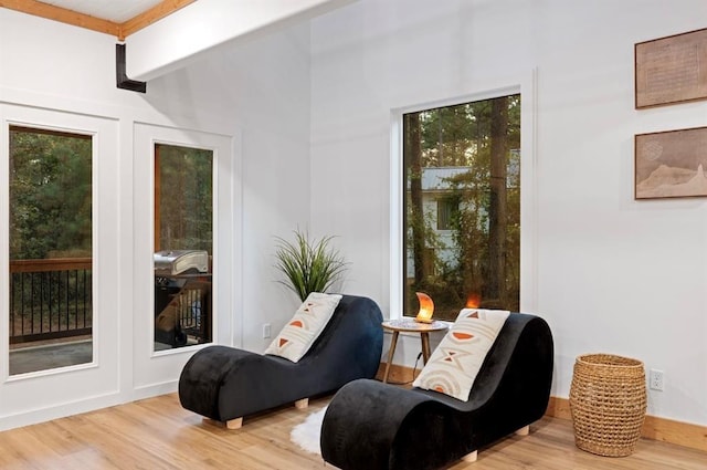 living area featuring beam ceiling and light hardwood / wood-style flooring