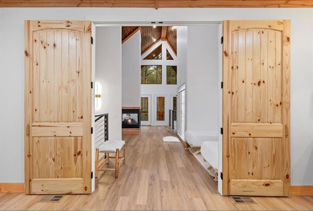 hallway featuring beam ceiling, hardwood / wood-style floors, and high vaulted ceiling