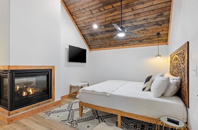 bedroom featuring vaulted ceiling, a multi sided fireplace, hardwood / wood-style flooring, ceiling fan, and wood ceiling