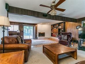 living room with light colored carpet, ceiling fan, and wooden walls