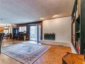 living room featuring a fireplace, parquet floors, a textured ceiling, and brick wall