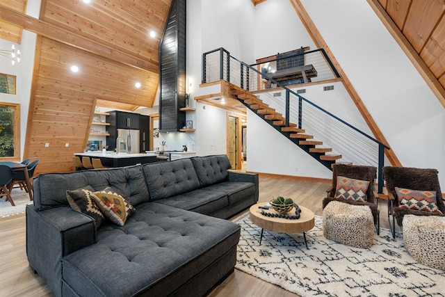 living room featuring wood walls, light hardwood / wood-style flooring, high vaulted ceiling, and sink