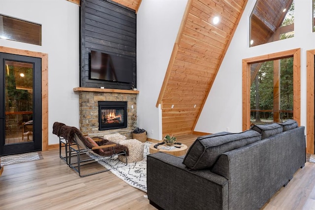 living room with a stone fireplace, wooden ceiling, light wood-type flooring, and high vaulted ceiling