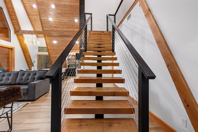 staircase with wood ceiling, wood-type flooring, high vaulted ceiling, and an inviting chandelier