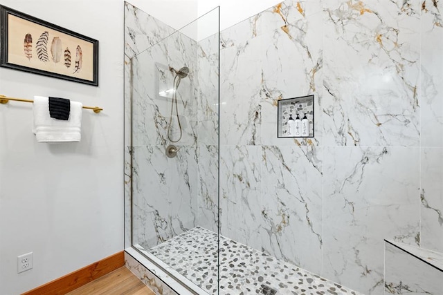 bathroom with tiled shower and hardwood / wood-style flooring