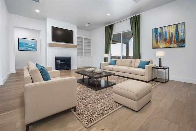 living room featuring a fireplace, light hardwood / wood-style floors, and built in features