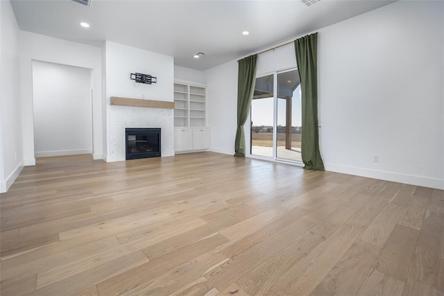 unfurnished living room with built in shelves and light hardwood / wood-style flooring