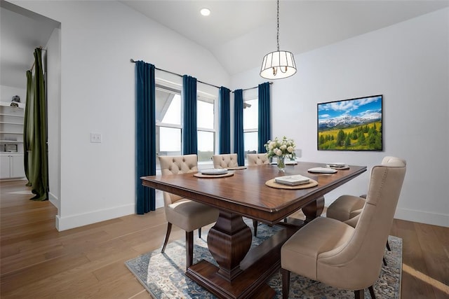 dining area with light wood-type flooring and vaulted ceiling