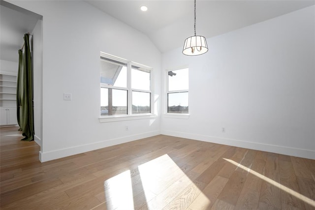 unfurnished dining area featuring a chandelier, light wood-type flooring, and vaulted ceiling