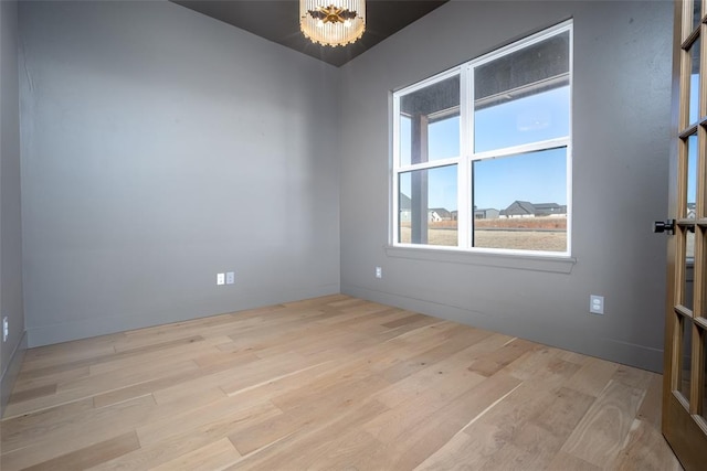 empty room featuring an inviting chandelier and light hardwood / wood-style flooring