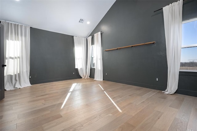 spare room with vaulted ceiling and light wood-type flooring