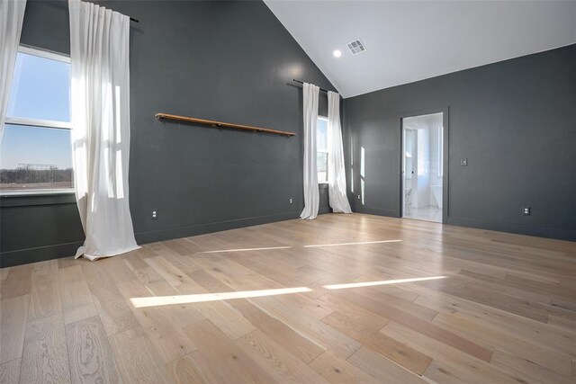 unfurnished room with light wood-type flooring and high vaulted ceiling