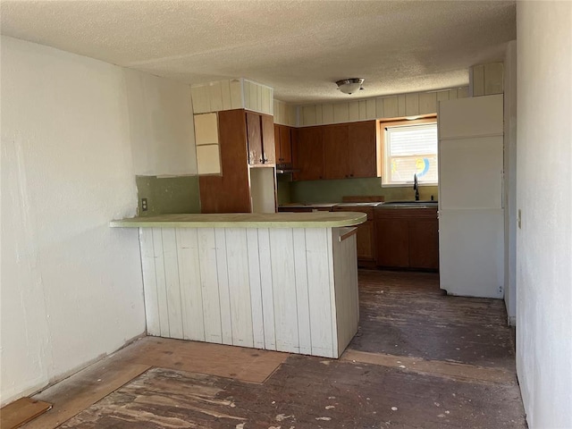 kitchen featuring kitchen peninsula, sink, and a textured ceiling