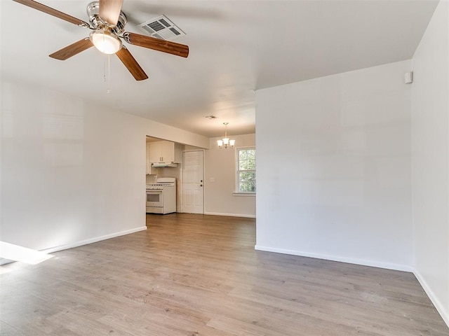 unfurnished living room featuring ceiling fan with notable chandelier and light hardwood / wood-style flooring