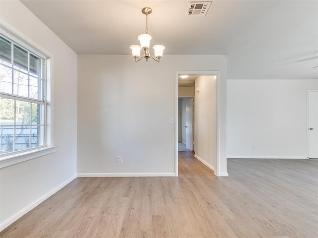 empty room featuring light hardwood / wood-style floors and a chandelier