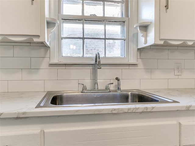 kitchen with decorative backsplash, white cabinetry, sink, and plenty of natural light