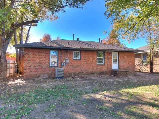 rear view of property featuring cooling unit and a lawn