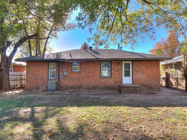 back of house with central air condition unit and a lawn