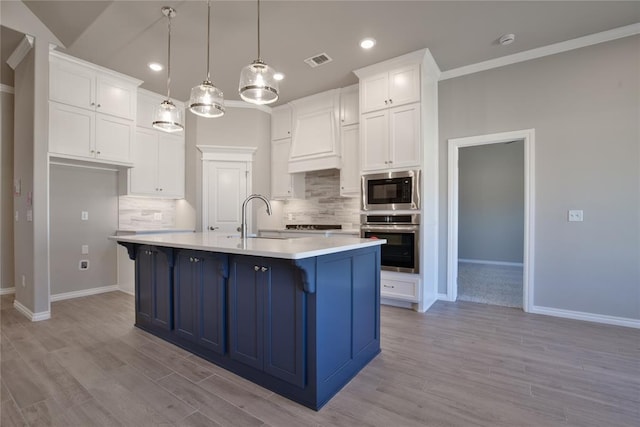 kitchen with backsplash, pendant lighting, a kitchen island with sink, and appliances with stainless steel finishes