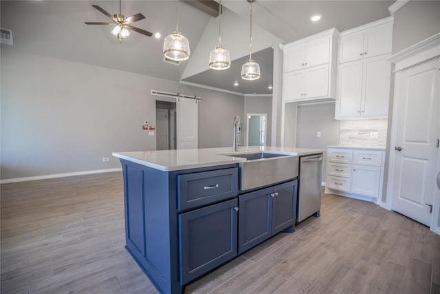 kitchen featuring white cabinets, dishwasher, a barn door, and a kitchen island with sink