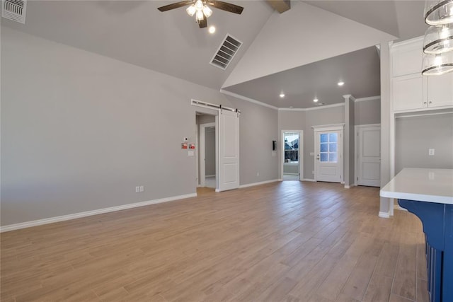 unfurnished living room with ceiling fan, a barn door, high vaulted ceiling, crown molding, and light hardwood / wood-style floors