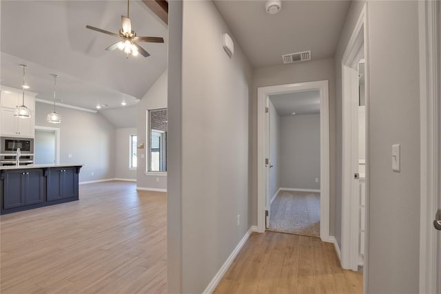 hallway with light hardwood / wood-style flooring, lofted ceiling, and sink