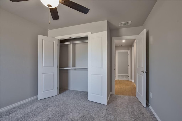 unfurnished bedroom featuring ceiling fan, a closet, and light colored carpet