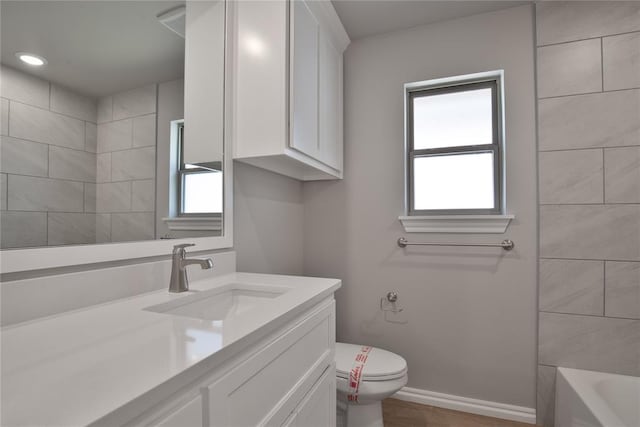 bathroom featuring a wealth of natural light, toilet, vanity, and hardwood / wood-style flooring