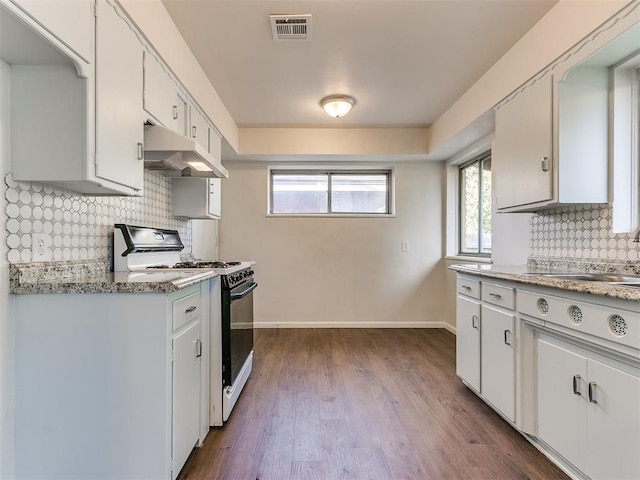 kitchen with tasteful backsplash, white cabinetry, dark wood-type flooring, and gas range gas stove