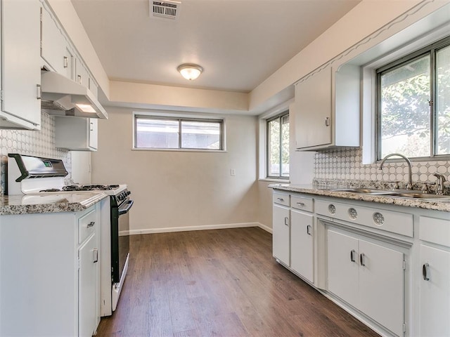 kitchen with gas range gas stove, sink, a healthy amount of sunlight, dark hardwood / wood-style flooring, and white cabinets