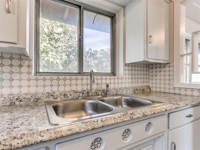 kitchen featuring decorative backsplash, white cabinetry, and sink