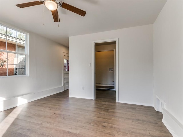 unfurnished room featuring hardwood / wood-style floors, ceiling fan, and a baseboard radiator