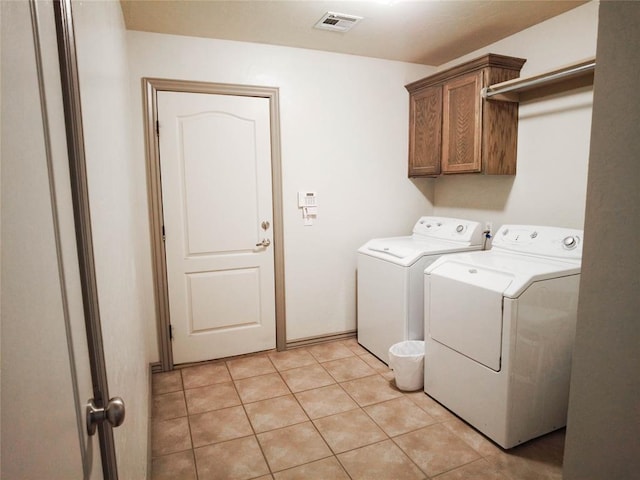 washroom featuring light tile patterned flooring, cabinets, and washing machine and clothes dryer