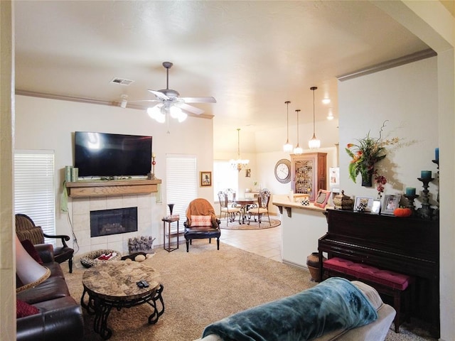 tiled living room featuring ceiling fan with notable chandelier, a wealth of natural light, crown molding, and a tile fireplace