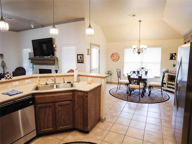 kitchen with a tile fireplace, sink, stainless steel appliances, and decorative light fixtures