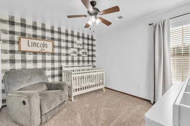 bedroom featuring a crib, light carpet, and ceiling fan