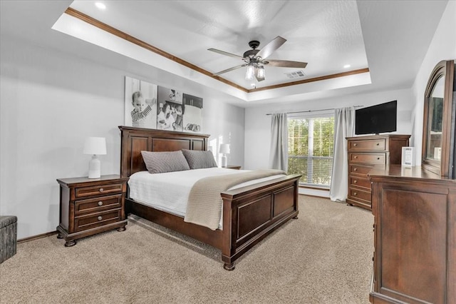 bedroom with ceiling fan, light colored carpet, ornamental molding, and a tray ceiling