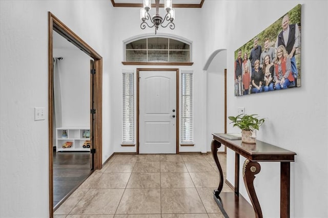 foyer entrance featuring light hardwood / wood-style floors, ornamental molding, a high ceiling, and a chandelier