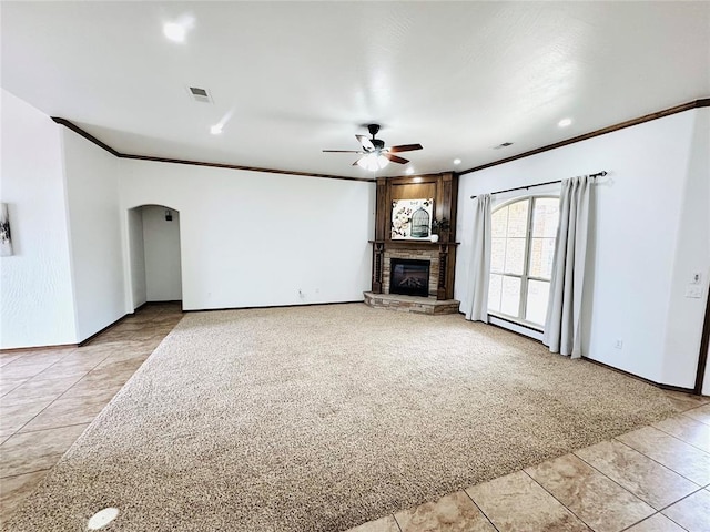 unfurnished living room featuring arched walkways, ceiling fan, a fireplace, visible vents, and crown molding