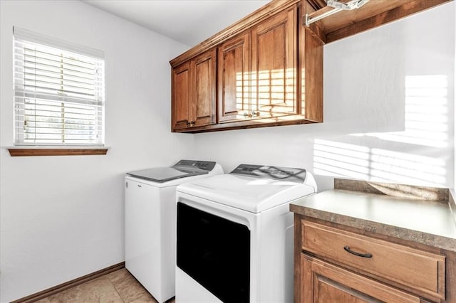 washroom with cabinet space, light tile patterned floors, baseboards, and washing machine and clothes dryer