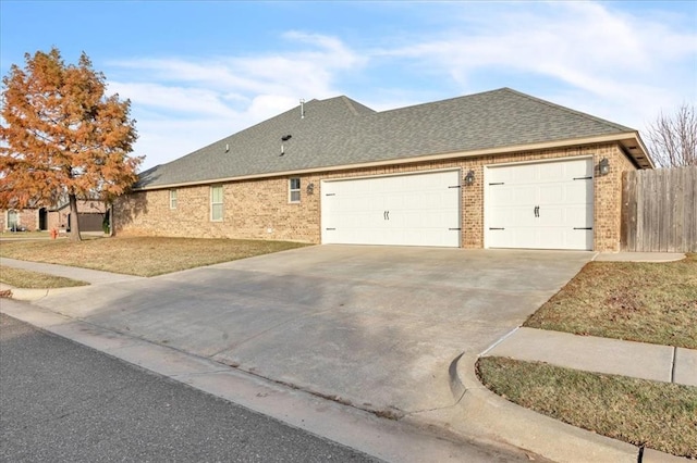 view of home's exterior with a garage, a shingled roof, brick siding, fence, and driveway